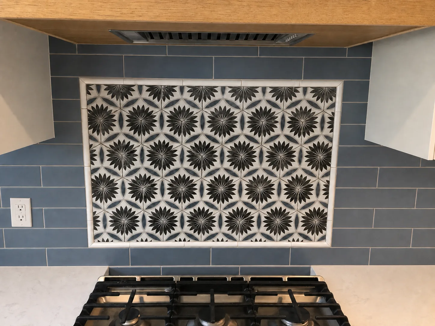 Patterned feature tile framed by blue field tile behind a kitchen range